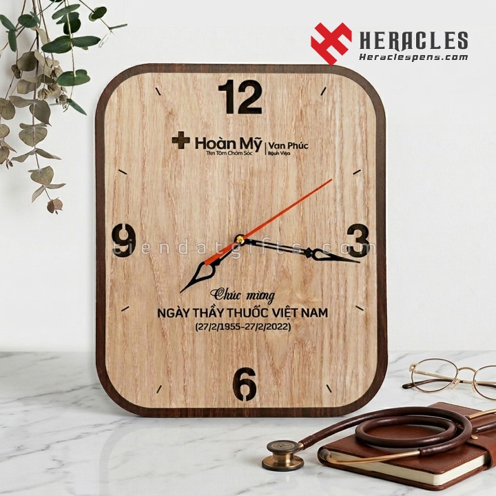 Đồng hồ gỗ treo tường in logo Bệnh viện Hoàn Mỹ Vạn Phúc chúc mừng Ngày Thầy thuốc Việt Nam cao cấp thiết kế hình chữ nhật bo góc tinh tế làm quà tặng.