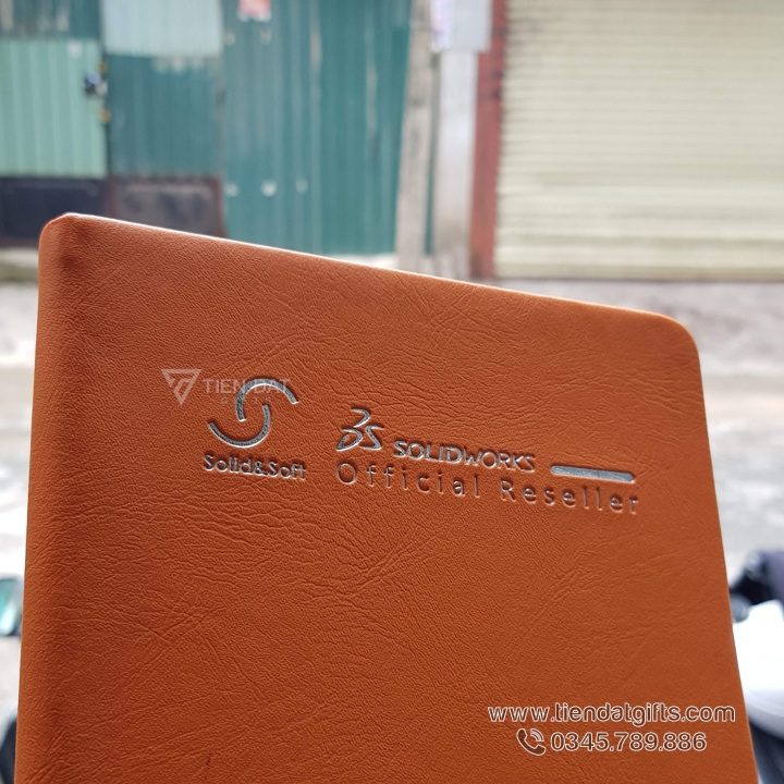 Sổ tay Địa ốc Thành Đô, bìa Simili nâu dập chìm logo, món quà tặng doanh nghiệp sang trọng cho đối tác. Cận cảnh chất liệu da Simili vân hạt, bền đẹp, chống nước, xưởng sản xuất và in sổ tay theo yêu cầu uy tín.
