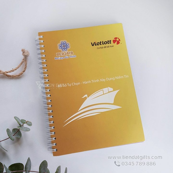 Sổ Lò Xo A5 bìa cứng màu vàng, in logo Vietlott và Berjaya, mẫu quà tặng doanh nghiệp thiết thực.
